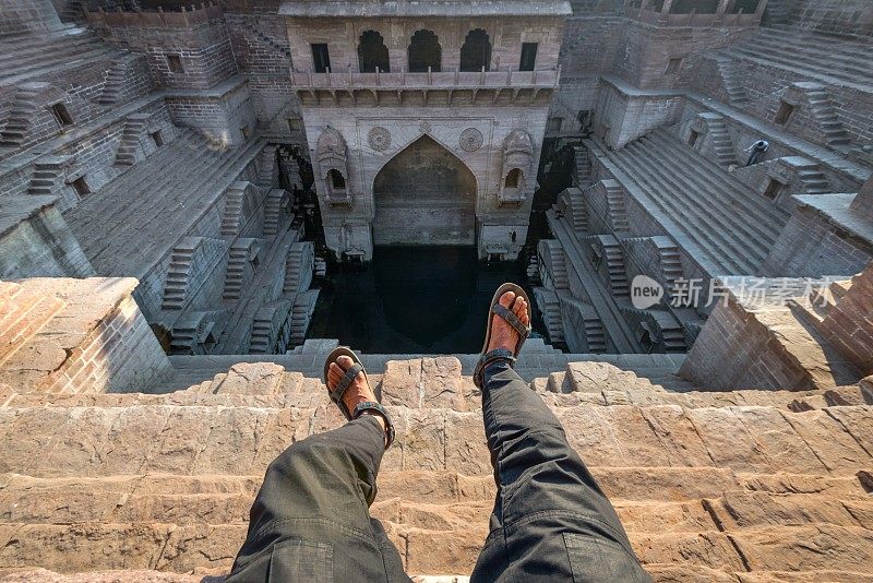 印度拉贾斯坦邦焦特布尔，一名游客在Toorji Ka Jhalra Bavdi世界著名的台阶上拍照。梯级井，通过一组梯级下降到水平面到达水的井